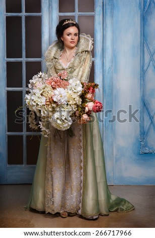 beautiful haughty queen in royal dress.Princess holding a large bouquet of flowers. Queen in the interior