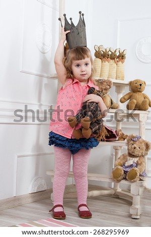 little girl in the crown among stuffed toys