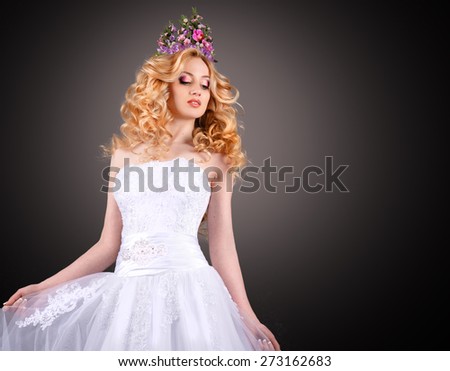 bride in white dress with perfect makeup and a crown of flowers on her head.curly-haired blonde with flowers in her hair