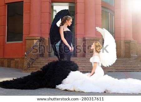 two angels. white and black angels.good and evil. black angel standing over white angel