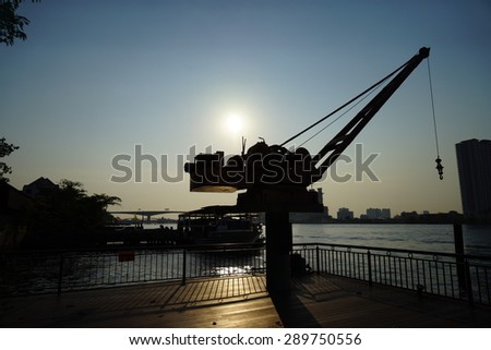 Silhouette of small crane at old port on side of Chao Phraya River, Bangkok