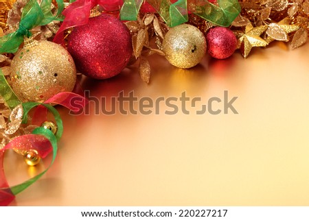 Christmas border with red and gold balls and ribbon with gold decorations laid on a matte gold surface. Space for copy.