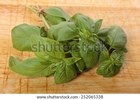 Bunch of fresh basil on an old wooden chopping board