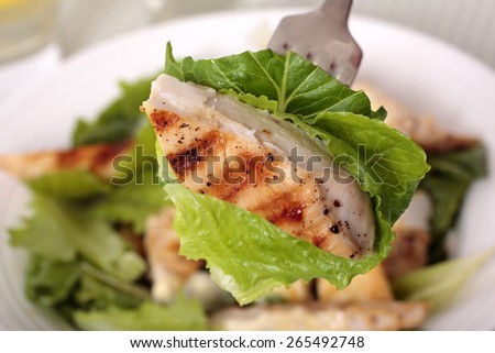 A piece of chicken caesar salad on the fork