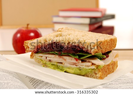School lunch: turkey sandwich with apple on book