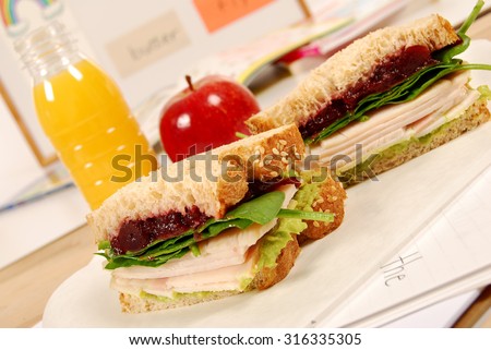 School lunch: turkey sandwich with apple and drink in classroom