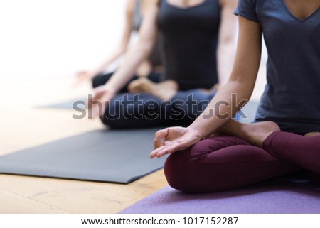 Women practicing yoga together and sitting in the lotus pose: mindfulness meditation, spirituality and healthy lifestyle concept