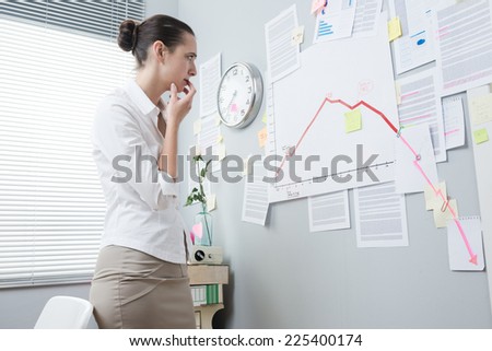 Office worker analyzing a financial chart on office wall with arrow going down.
