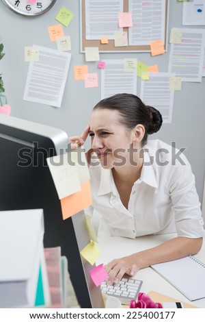 Tired female white collar working at computer with eye pain touching her temples.