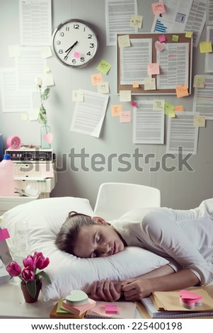 Tired businesswoman sleeping in office desk overnight.