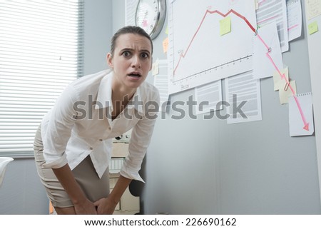 Stunned businesswoman checking a financial business chart on office wall with arrow going down.