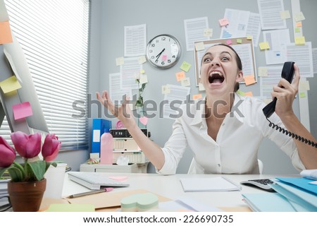 Angry stressed businesswoman in office shouting at phone.