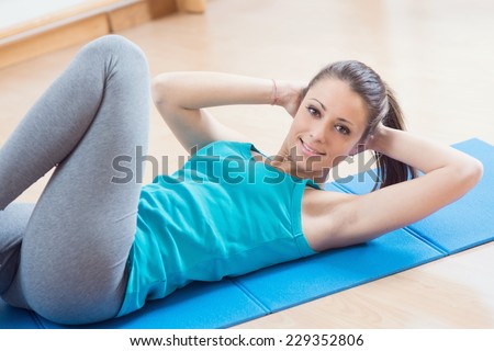 Attractive woman doing abs workout at gym for muscle toning and flat stomach.