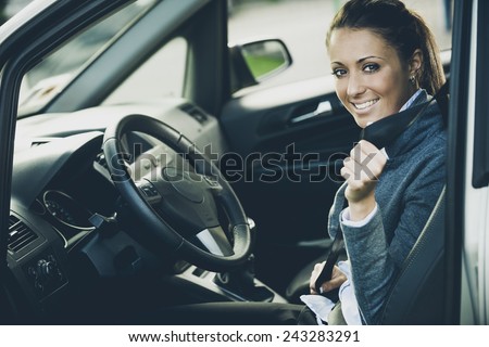 Young attractive woman sitting on car seat and fastening seat belt, car safety concept.