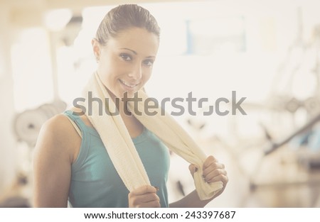 Attractive young woman with towel at gym smiling at camera.