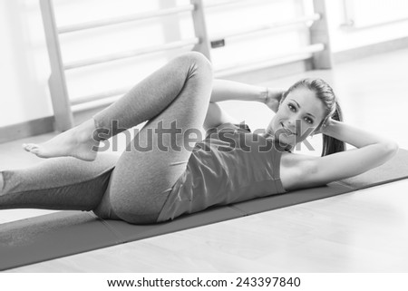 Attractive woman doing abs workout at gym for muscle toning and flat stomach.