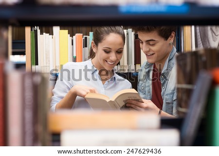 Smiling young students searching for books at the library