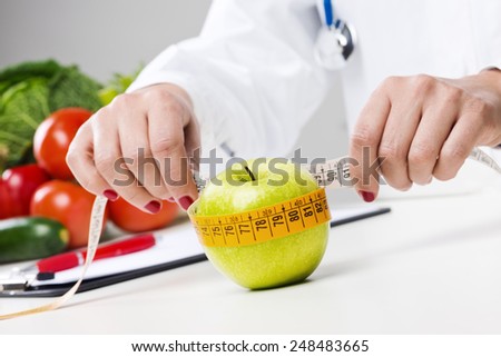 Nutritionist measuring an apple with measuring tape, dieting and weight loss concept