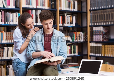 Young students studying and reading a book together at the library