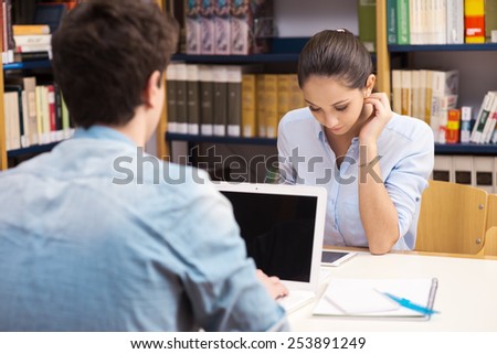 Young students sitting at desk and studying with laptop and tablet