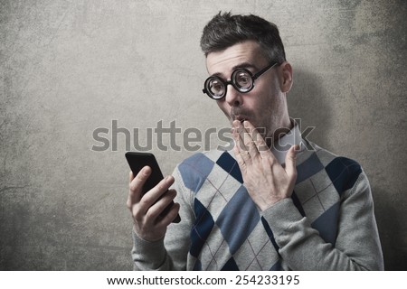 Funny guy having troubles with his smartphone, hand over mouth