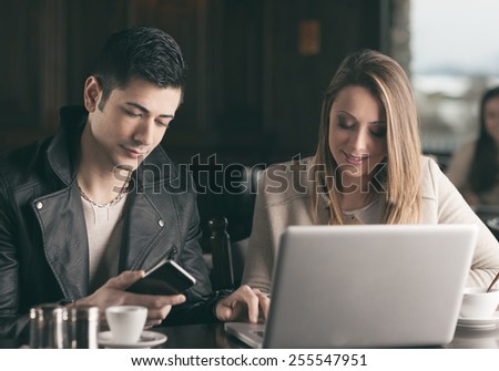 Cheerful couple at the cafe connecting to internet using a laptop