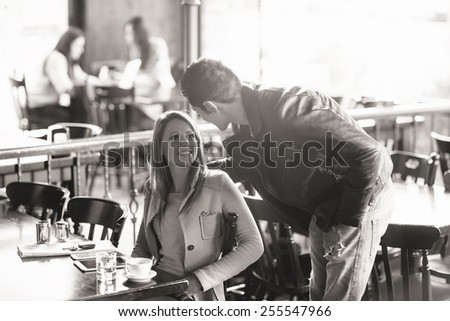 Beautiful smiling woman and stylish man meeting at the bar, he is touching her back