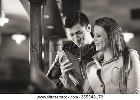 Fashionable couple spending time together, she is holding a mobile touch screen phone