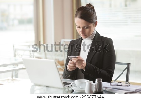 Busy elegant woman at the bar working on her computer next to a window