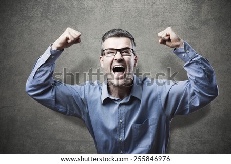 Joyful businessman with fists raised receiving good news and shouting