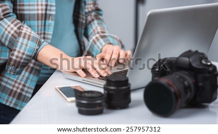 Female photographer working in her studio hands close up and digital camera on foreground