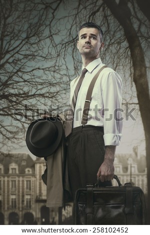 Vintage businessman holding briefcase, hat and coat