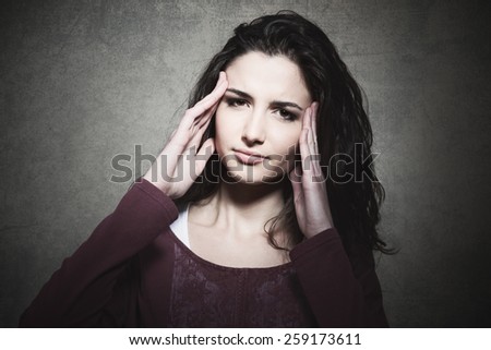 Sad tired young woman with headache touching her temples