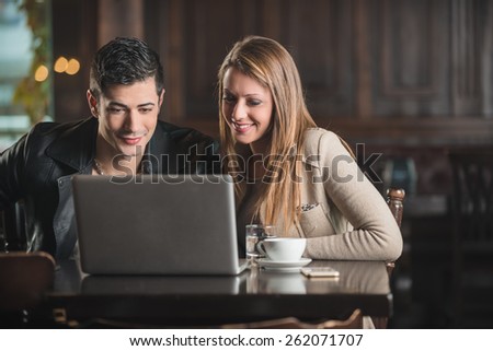 Cheerful couple at the cafe connecting to internet using a laptop