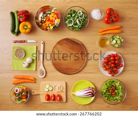Creative vegetarian cooking at home concept with fresh healthy vegetables chopped, salads and kitchen wooden utensils, top view with copy space