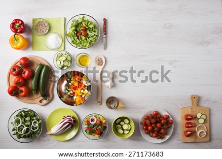 Healthy eating concept with fresh vegetables and salad bowls on kitchen wooden worktop, copy space at right, top view