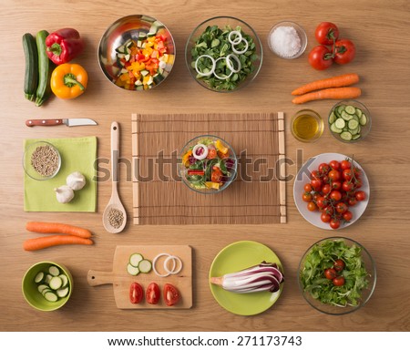Creative vegetarian cooking at home concept with fresh healthy vegetables chopped, salads and kitchen wooden utensils, top view with copy space
