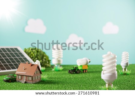 Environmental friendly toy town with model house, CFL lamps as trees and tractor carrying a light bulb