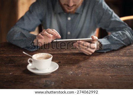 Young man using a digital touch screen tablet on a wooden table, hands close up