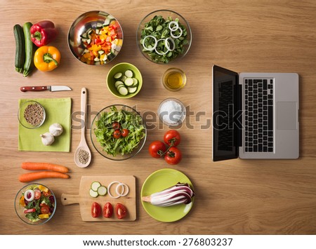 Online recipes concept with fresh vegetables, food ingredients and laptop on the right, top view