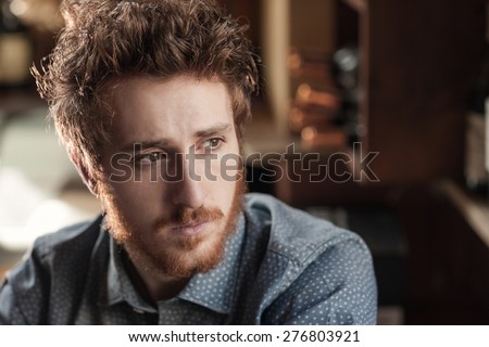 Hipster young man looking away with wine bottles on background