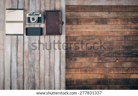 Grunge hipster wooden desktop with vintage camera, organizer, mobile and notebook, blank copy space