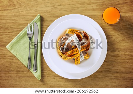 Healthy diet and weight loss concepts, table set on a wooden table with fruit juice and tape measure in a dish