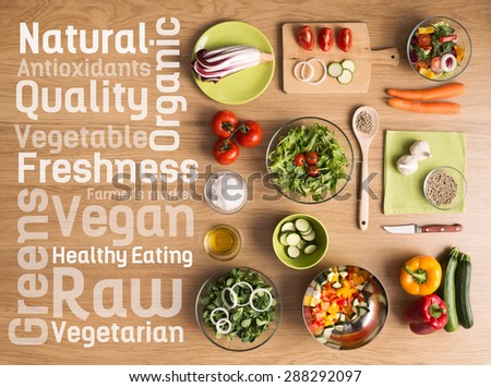 Creative vegetarian cooking at home with fresh healthy vegetables chopped, salads and kitchen wooden utensils, healthy eating text concepts on the left