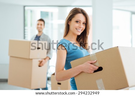 Happy smiling couple moving in a new house and carrying carton boxes, relocation and renovation concept