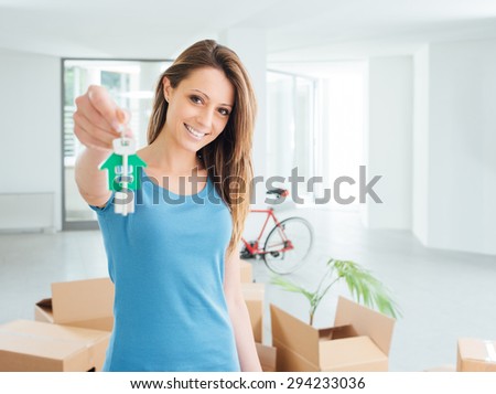 Beautiful smiling woman holding house keys of her new house, real estate and relocation concept
