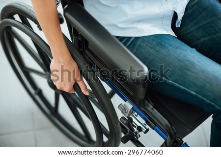 Woman in wheelchair\'s hand on wheel close up, disability and handicap concept