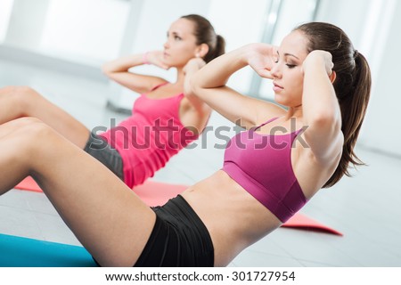 Young fit women at the gym doing abs workout on a mat, healthy lifestyle and fitness concept