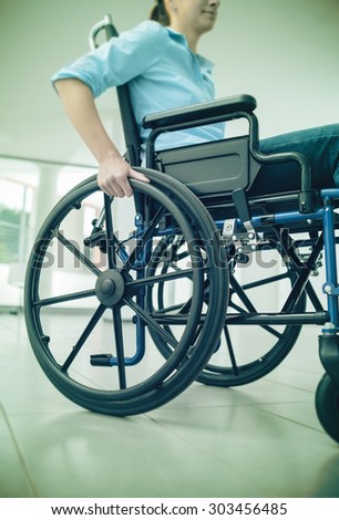 Young woman in wheelchair hand pushing on wheel close up, disability and handicap concept