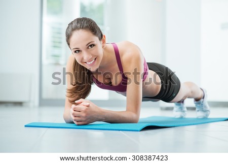 Smiling woman exercising at the gym on a mat, fitness and workout concept